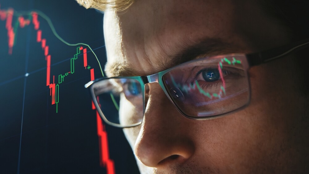 A close-up view of a trader with a stock graph in the background.